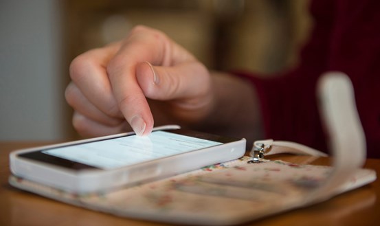 En hand scrollar på en mobiltelefon