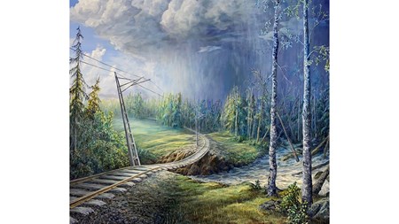 Tågräls går genom landskap, över raserad banvall där å forsar. Träd har vält vid ån i skog längre bort. Oväder på himlen.