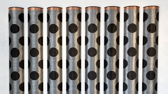 En bildväv med åtta stycken metalliska, silverfärgade vävda ”rör” som är täckta av svarta rundlar som ser ut som hål. 