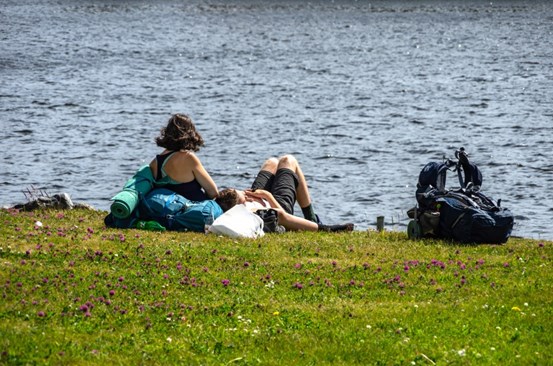 Två personer solar vid vatten.