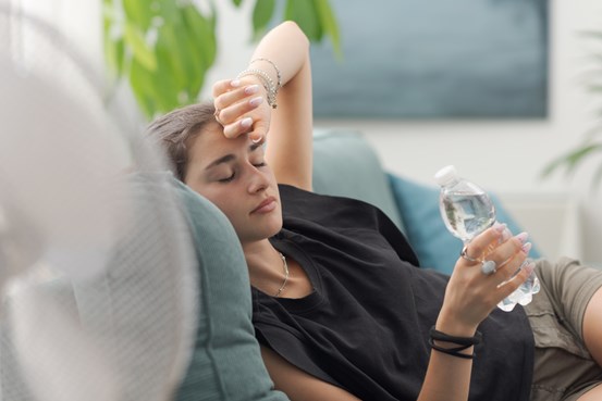 kvinna framför fläkt dricker vatten