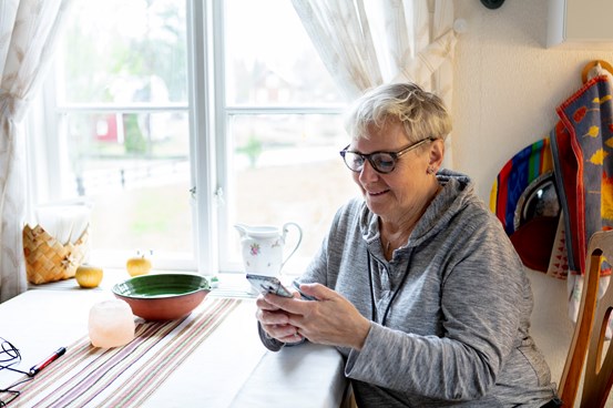 Donna che tiene un telefono cellulare e legge su di esso.