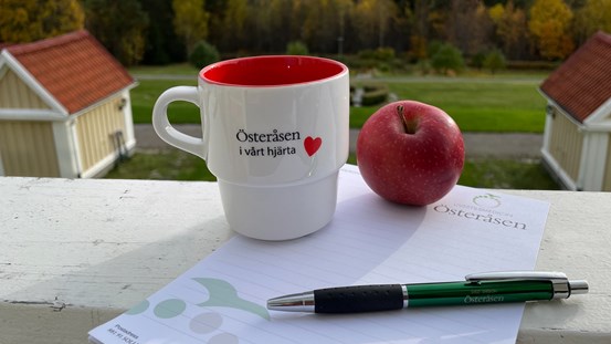 Penna på ett papper med en mugg och ett äpple.