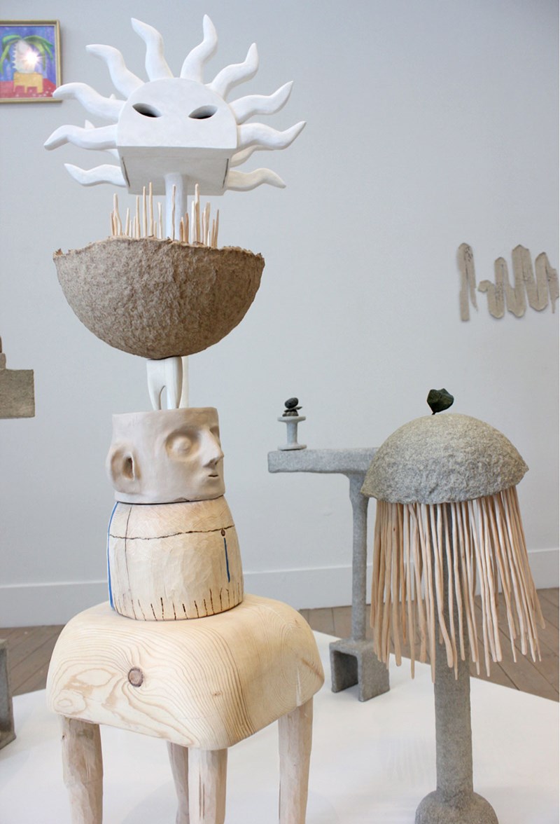 Ett lågt podium med en samling skulpturer i abstrakta och surrealistiska former av trä, gips, lera och pappersmassa. 