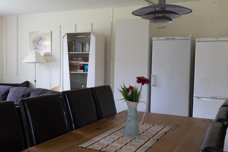 Gemensamt rum med matbord, kylskåp och soffa