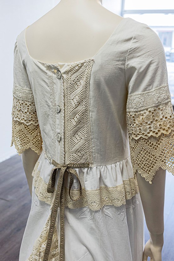 En provdocka iförd vit brudklänning i lakansväv och spets.