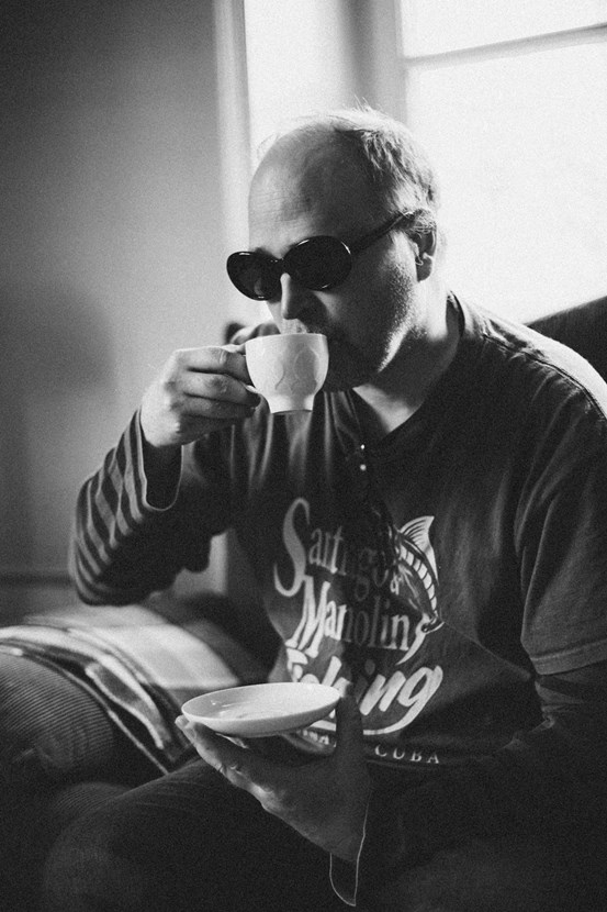Svartvitt porträttfoto av man som dricker kaffe.