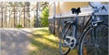 En cykel står lutad mot en av Österåsens byggnader. Skog syns i bakgrunden