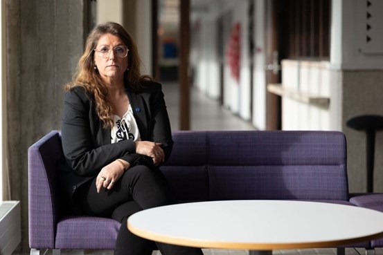 Anna Strandh sitter på en soffa en tittar in mot kameran. 