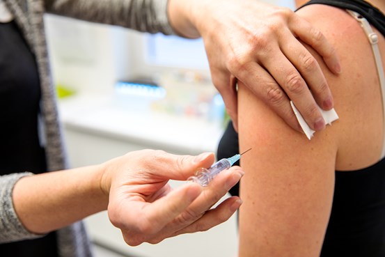 Vaccinationsbild där någon får en spruta med vaccindos covid-19