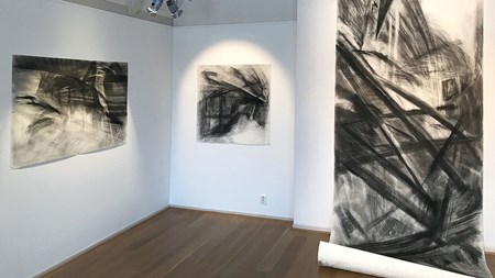 Foto. Vy över utställning, tre bilder ur en serie svart-vita teckningar sitter uppsatta på väggarna.