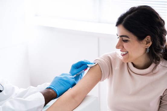En kvinna får sin vaccindos av vårdpersonal.