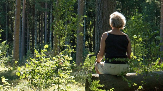 Person sitter på en sten ute i skogen