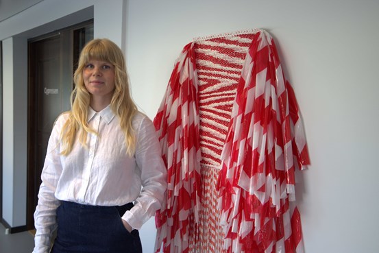 Konsthandläggaren Lovisa står framför ett rött och vitt konstverk i Regionens hus.