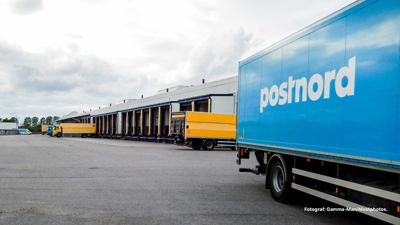 Lastbilar från PostNord vid en terminal med lastkajer för distribution och logistik