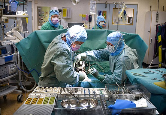Operationssal  där fyra vårdmedarbetare står runt operationsbordet 