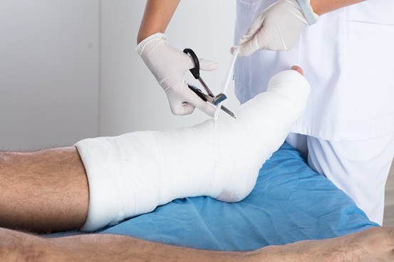 En läkare arbetar med att lägga ett förband på en patients fot