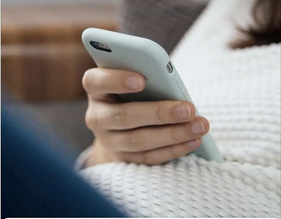 Hand som håller i en mobiltelefon.