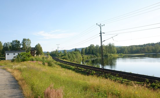 Järnväg i naturlandskap vid vattendrag.