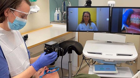 Emelie De Geer filmar ner på en patients mun som sedan syns på en skärm i bakgrunden.