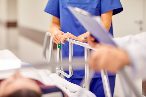 Vårdpersonal står vid en patients säng.