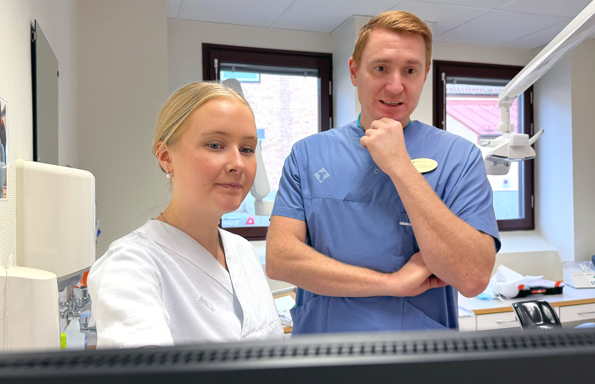 alt='Mats Ellner, verksamhetschef Folktandvården Medelpad handleder nya tandläkare Magdalena Gjertz. De står i ett behandlingsrum och studerar något på en datorskärm.'