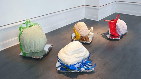 Fyra skulpturala objekt på ett mörkt golv. Beskrivning finns i brödtext. 