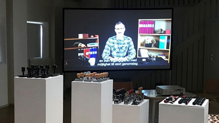 På flera podium står mängder med olika sorters stämplar uppradade. I bakgrunden syns en skärm där en video spelas upp.