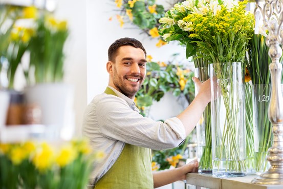 Florist som jobbar med växter vid stor blomvas
