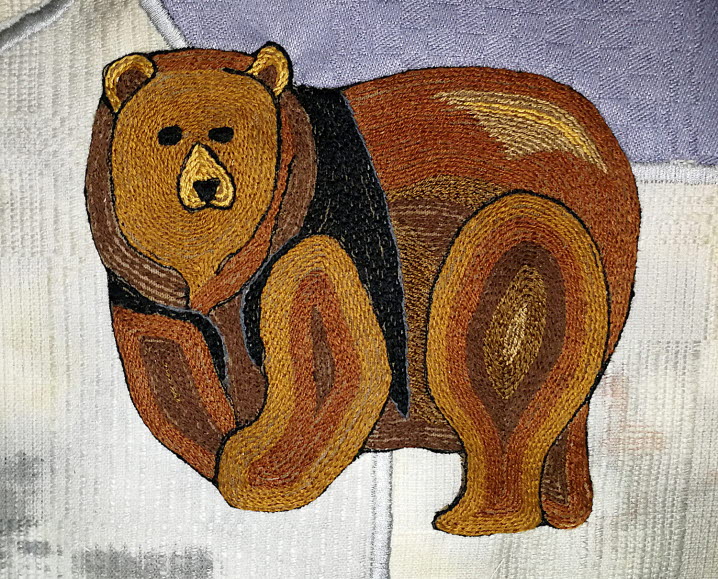 Detalj av Ida Isak Westerbergs textila verk ”Paradiset på jorden” som visar en broderad brunbjörn.