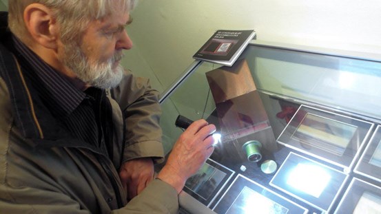 Åke Hultman belyser en daguerreotyp vid utställningen i Örnsköldsvik.
