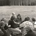 Personer, en med gitarr, på en gräsmatta med en björkskog bakom..