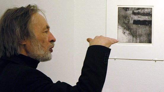 Fotografi av konstnären Christer Carlstedt framför ett grafiskt verk, vid utställning på Grafiska Sällskapet 2013.
