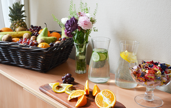 En bänk med färsk frukt, vatten i karaffer, godis och en blombukett.