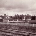 Träbyggnader med ett staket och ett tågräls framför.