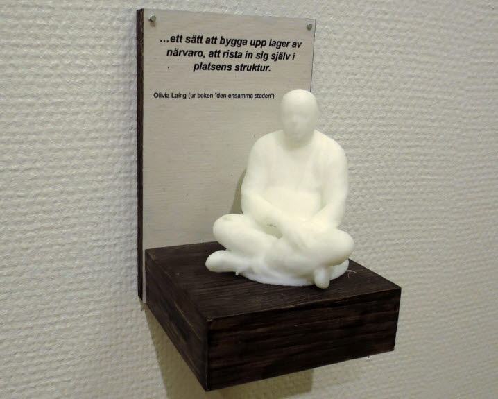 Lars Ahlström, ett av hans skulpturala objekt vid utställningen 2019. Visar en sittande Buddhagestalt med citat från Olivia Laing inskrivet ovanför: ”… ett sätt att bygga upp lager av närvaro, att rista in sig själv i platsens struktur.” 