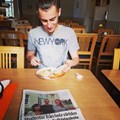En deltagare sitter i matsalen och äter smörgåsar med en tidning framför sig.