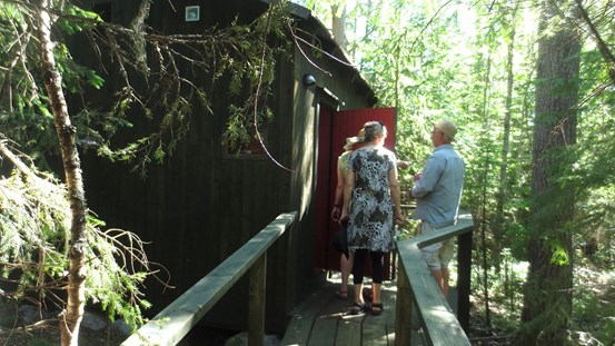 Fotografi visar tre personer som står vid entrén till Konstbiotopens hus i Järnäs.