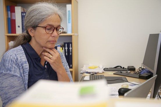 Maria Alsén Lindström sitter vid sin dator och läser på skärmen.
