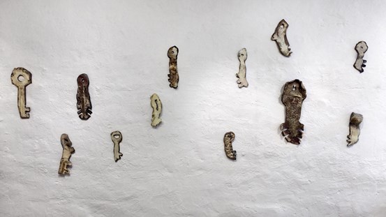 Mot en vit vägg hänger 12 nycklar i rakubränt stengods, skulpterade av Petter Dahlström Persson.