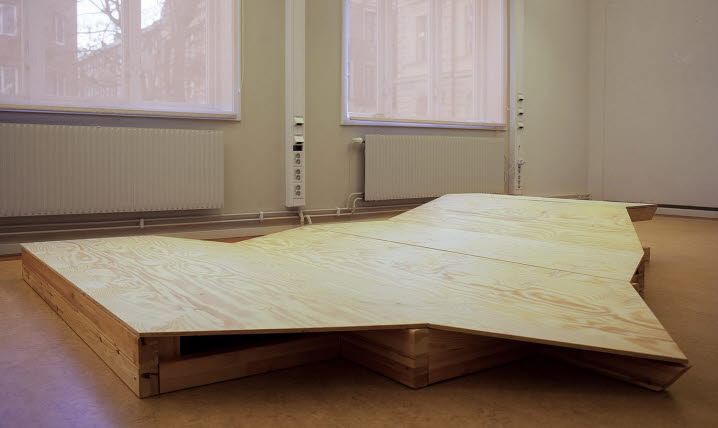 Madeleine Hertz obehandlade träkonstruktion ”Plats 1” som ligger på gallerigolvet. Formen är hämtad från taket på en utomhusscen i Timrå.