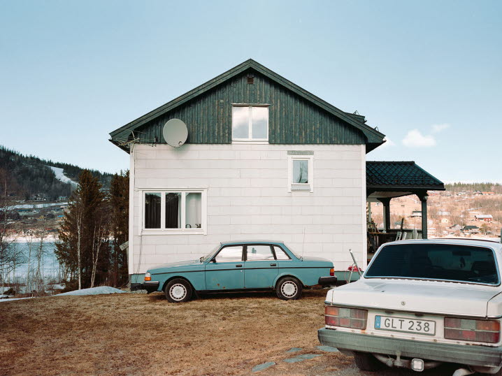 Fotografi av hus med eternitplattor. Utanför står två Volvobilar av äldre modell.