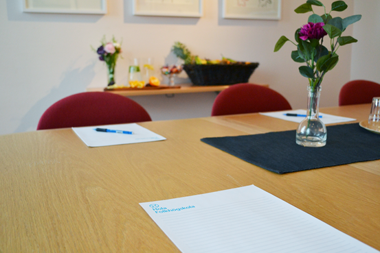 Ett bord i ett konferensrum dukat med skrivblock och blommor.