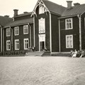 Större trähus med vita knutar och snickarglädje.