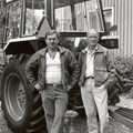 Två personer framför en traktor.