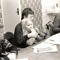 Några personer i en kurssal, bland annat person med ett barn i knät som dricker festis.