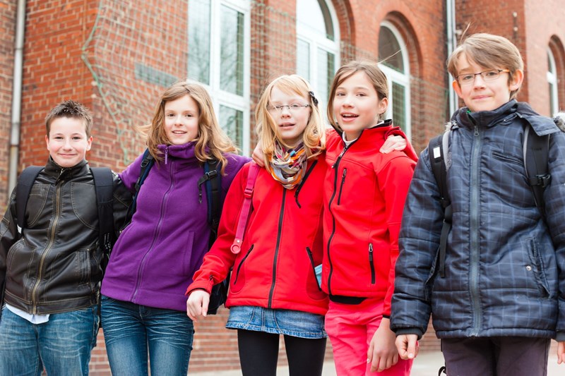 En grupp barn på rad utanför skolbyggnad