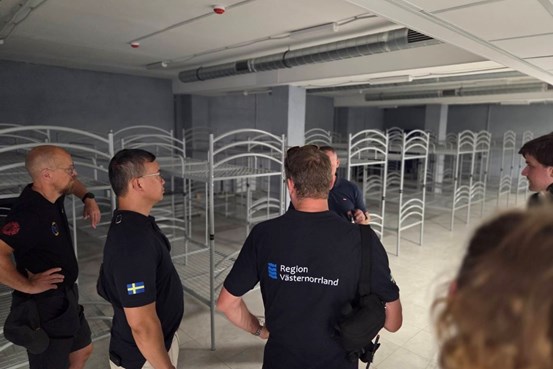 Rum med våningssängar där flera personer står samlade.