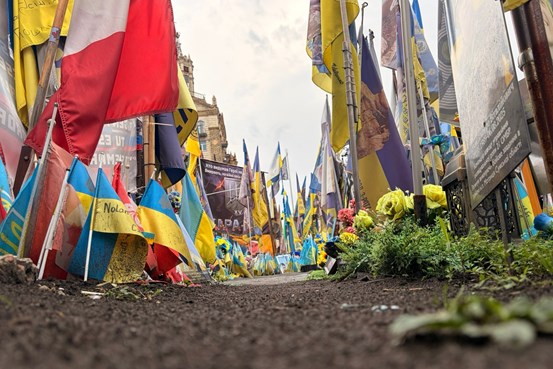 Minnesplats på Majdan i Kyiv med ukrainska flaggor, blommor och minnesskyltar längs en gångväg.