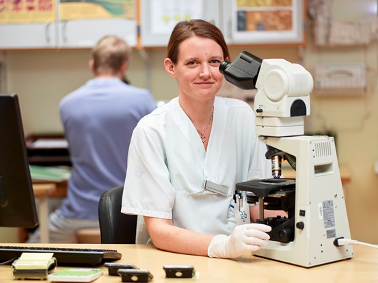 Biomedicins analytiker arbetar vid ett mikroskop